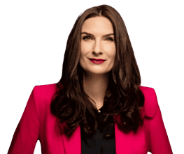 Frau mit langem braunem Haar, trägt einen leuchtend rosa Blazer und ein schwarzes Oberteil, blickt leicht nach oben und hat einen neutralen Gesichtsausdruck.